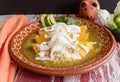 Closeup of delicious Mexican green enchiladas with sour cream and cheese, in a red patterned bowl