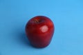 Closeup of a delicious red apple in front of a blue background