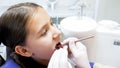 Closeup image of dentist hands in gloves examining girls teeth with instruments