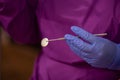 Closeup of a dentist wearing gloves and holding a dental mouth mirror