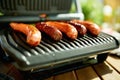 Closeup on desk with electric grill and grilled sausages Royalty Free Stock Photo
