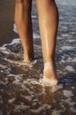 Closeup detail of female legs walking along the seashore.