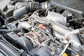 Closeup detail of a Flat-four car engine compartment under the open hood. Alternator and intake manifold