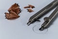 Closeup detail of a geometry pencil compass and pencil sharpening wood shavings on white paper with a drawn circle