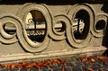 gray rough stone balustrade closeup. ornate motif. dry autumn leaves