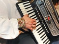 Closeup detail of hands playing a black accordion