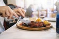 The hands of a woman eating an octopus plate with potatoes