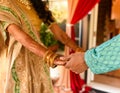 Closeup detail of an Indian bride and groom wearing beautiful colorful garments holding hands Royalty Free Stock Photo
