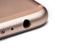 Closeup detail of 3.5mm audio jack connector hole on bottom of rose gold coloured mobile phone, isolated white background Royalty Free Stock Photo