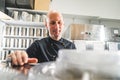 Closeup of detail of professional pastry machinery with smiling chef standing next to it. Bald caucasian man in black