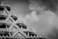 Closeup detail of temple in Thailand. Art pattern. Traditional Thai style sculpture against clouds and sky. Black and white scene Royalty Free Stock Photo