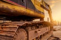 Closeup dirt track pad of backhoe. Digger parked at construction site. Bulldozer near concrete pole. Earth moving machine. Yellow Royalty Free Stock Photo