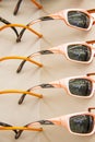Closeup of display of orange-pink sports sunglasses with identical refletctions in lenses