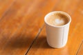 Closeup of disposable takeaway paper cup of hot coffee latte with heart shape art milk foam with lid cover on wooden table Royalty Free Stock Photo