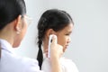 Closeup of Doctor examines or treatment child patient temperature in the ear using electronic thermometer on white background, Royalty Free Stock Photo