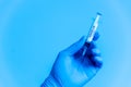 Closeup of doctor hand with gloves holding covid-19 vaccine syringe on blue background. concept of science and coronavirus vaccine Royalty Free Stock Photo