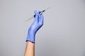 Closeup doctor or nurse hand in rubber latex medical purple glove holding a transparent syringe with sharp needle. ÃÂ¡oncept