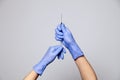 Closeup doctor or nurse hands in rubber latex medical purple gloves holding a transparent syringe with sharp needle. ÃÂ¡oncept