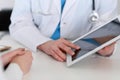 Closeup of a doctor and patient sitting at the desk. Physician pointing into tablet pc. Medicine and health ca Royalty Free Stock Photo