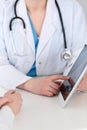 Closeup of a doctor and patient sitting at the desk. Physician pointing into tablet pc. Medicine and health ca Royalty Free Stock Photo
