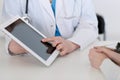 Closeup of a doctor and patient sitting at the desk. Physician pointing into tablet pc. Medicine and health ca Royalty Free Stock Photo