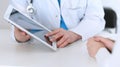 Closeup of a doctor and patient sitting at the desk. Physician pointing into tablet pc. Medicine and health ca Royalty Free Stock Photo