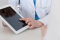 Closeup of a doctor and patient sitting at the desk. Physician pointing into tablet pc. Medicine and health ca Royalty Free Stock Photo