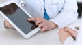 Closeup of a doctor and patient sitting at the desk. Physician pointing into tablet pc. Medicine and health ca Royalty Free Stock Photo