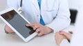 Closeup of a doctor and patient sitting at the desk. Physician pointing into tablet pc. Medicine and health ca Royalty Free Stock Photo