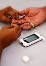 Doctor piercing the finger of patient with lancet to check blood sugar leve