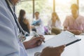 closeup of doctor with stethoscope and with medical documents in hands, patients are on the background Royalty Free Stock Photo