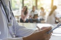 closeup of doctor with stethoscope and with medical documents in hands, patients are on the background Royalty Free Stock Photo