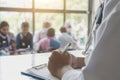 closeup of doctor with stethoscope and with medical documents in hands, patients are on the background Royalty Free Stock Photo