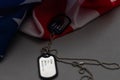 Closeup of a dog tag with the text thank you veterans engraved in it, next to a flag of the United States background. Royalty Free Stock Photo
