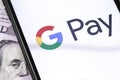 Closeup dollars and smartphone with Google Pay logo on the screen