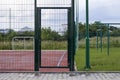 Closeup of door gate entrance to soccer or football field playground with bright red soft rubber flooring and protective net fence Royalty Free Stock Photo