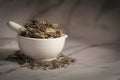 Closeup of Dry Mayurshikha leaves, in white ceramic mortar and pestle.