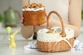Closeup of Easter basket with painted eggs on white marble table near woman with cake, focus on food