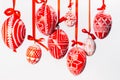 Closeup Easter eggs with folk Ukrainian pattern hang on red ribbons with bows on white background. Ukrainian traditional eggs Royalty Free Stock Photo