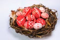 Closeup Easter red eggs with folk white pattern inside bird nest on white background