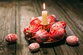 Closeup Easter red eggs with folk white pattern lay around on brass candlestick with burning candle and scattered eggs on rustic t