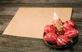 Closeup Easter red eggs with folk white pattern lay around on brass candlestick beside paper on rustic wood board. Ukrainian tradi