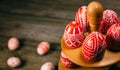Closeup Easter red eggs with folk white pattern lay around stand for eggs which stand on rustic wood background and eggs scattered