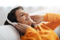 Closeup eastern woman reclining on couch, listening to music