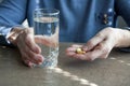 Closeup of elderly woman hand holding pills and glass of drinking water. Senior woman is going to take medicines for illnesses. Royalty Free Stock Photo