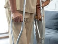 Closeup elderly woman`s hands holding on crutches standing in living room at home.