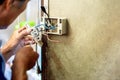 Closeup electric repair technician holding screwdriver and fixing the electric outlet Royalty Free Stock Photo