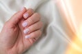 Closeup elegant pastel natural modern design manicure on fabric silk background. Female hands. Gel nails. Nude manicure Royalty Free Stock Photo