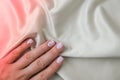 Closeup elegant pastel natural modern design manicure on fabric silk background. Female hands. Gel nails. Nude manicure Royalty Free Stock Photo