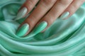 A closeup of an elegant woman's hand with well-groomed nails, holding a light green fabric. The background is a soft Royalty Free Stock Photo